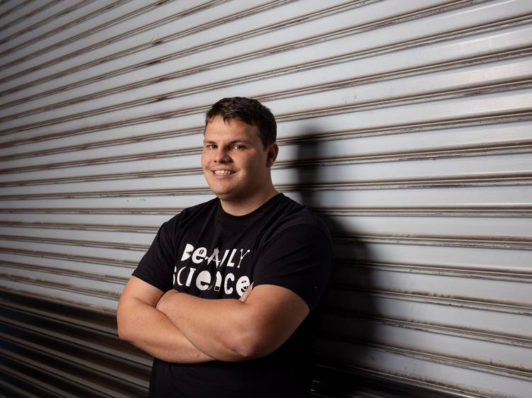 Corey Tutt, founder of Deadly Science, leaning against a corrugated shutter