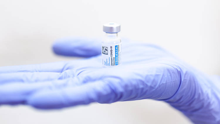 A hand holding a vial of vaccine