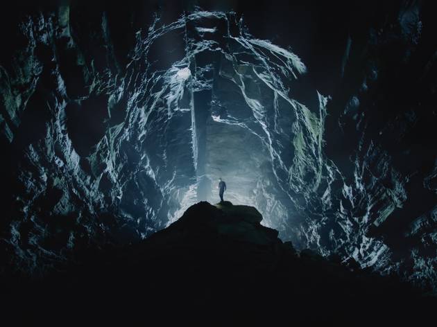 Invocation Trilogy, Carriageworks A stunning shot of a man in the distance in an underground cave that's lit up eerily blue
