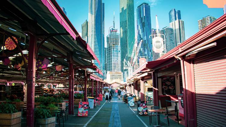 People walking through the sheds at Queen Victoria Market. The city skyline can be seen in the background