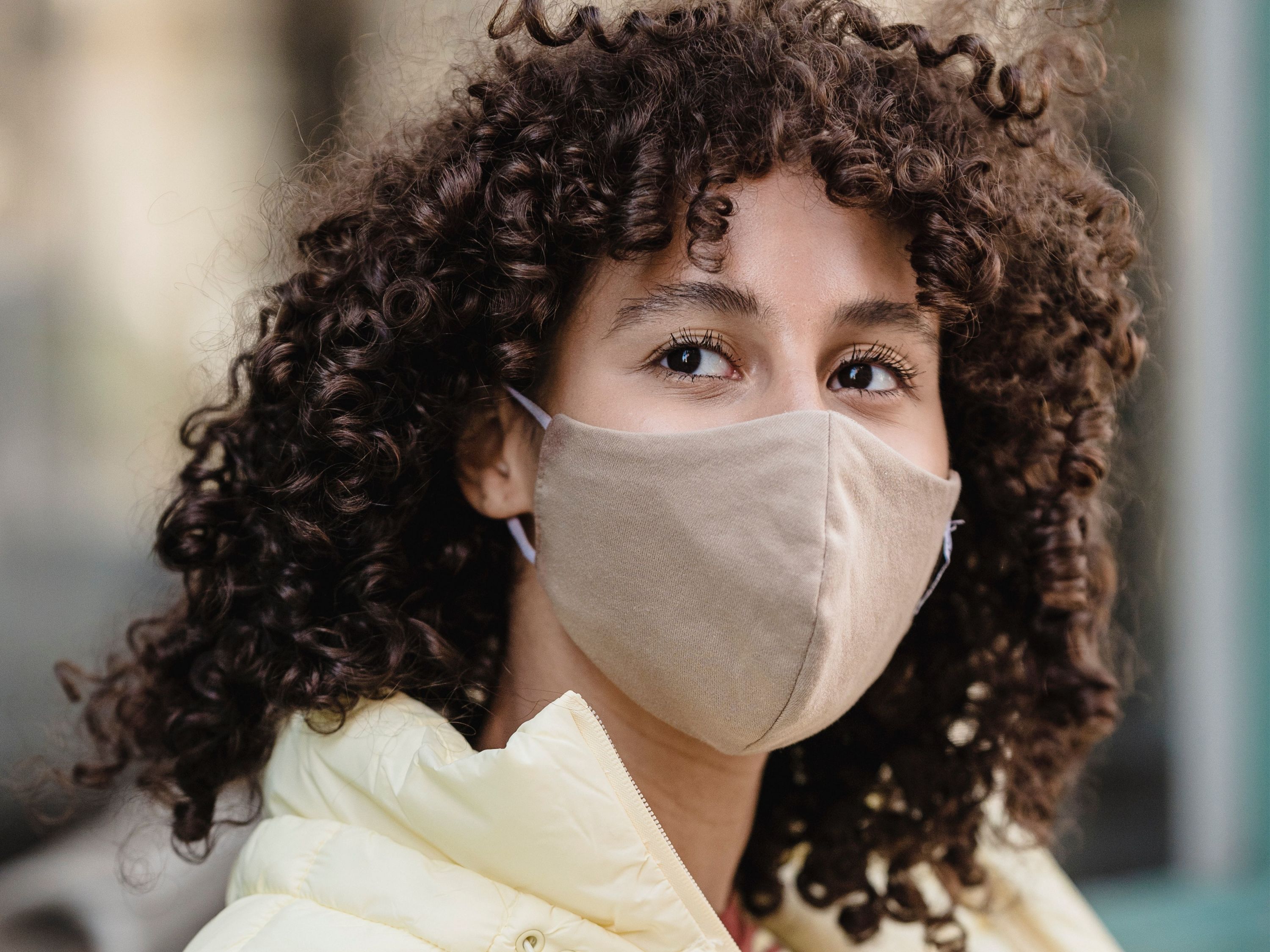 Woman in yellow jacket wearing a beige mask