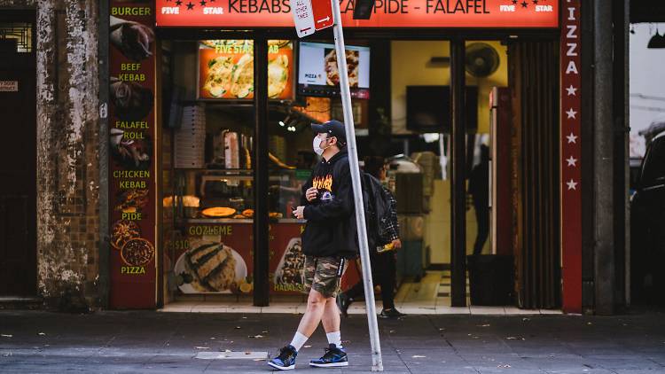 Man wearing a mask outside a kebab shop