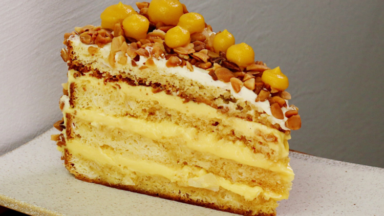 A layered vanilla cake with orange gel topping on a white square plate