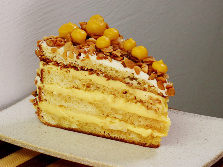 A layered vanilla cake with orange gel topping on a white square plate