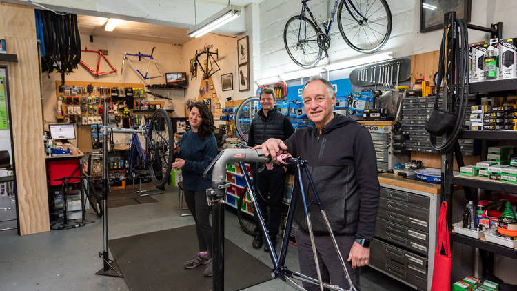 Three people in a bike shop. 