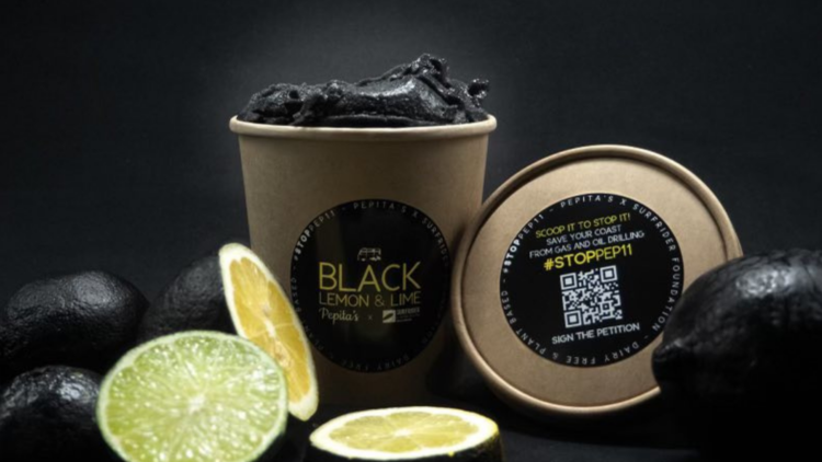 a black background, lemons painted black and a cardboard tub with black icecream