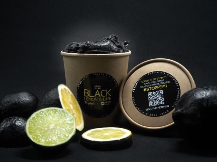 a black background, lemons painted black and a cardboard tub with black icecream