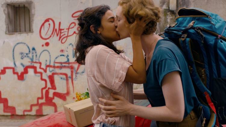 Two woman kiss in a graffitied street in Tel Aviv