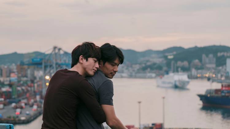 Two boys hug in Taiwan against a pink sunset in the film Dear Tenant