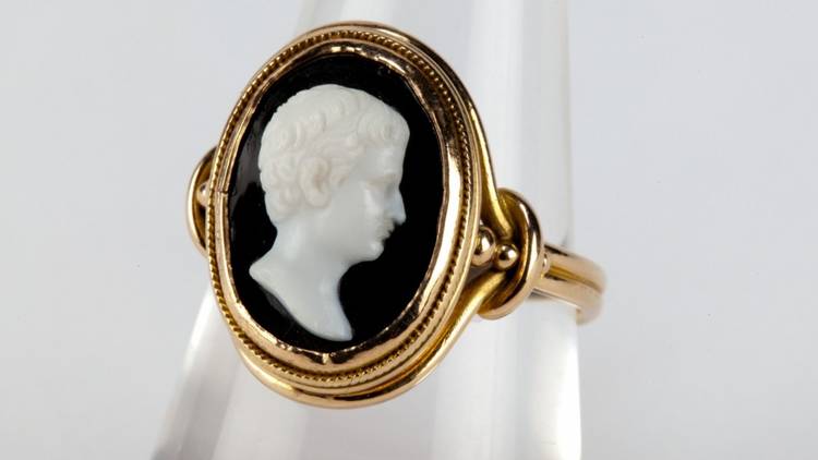 A gold ring with dark setting and a pale white face detail