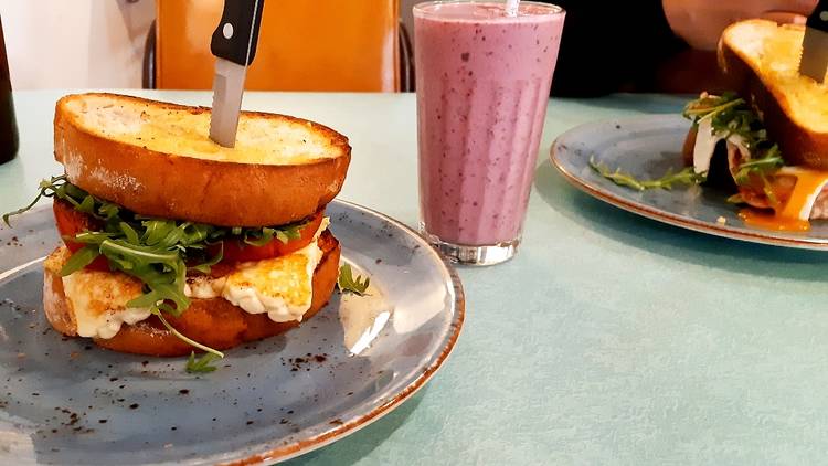 A sandwich with a knife sticking out of it and a smoothie