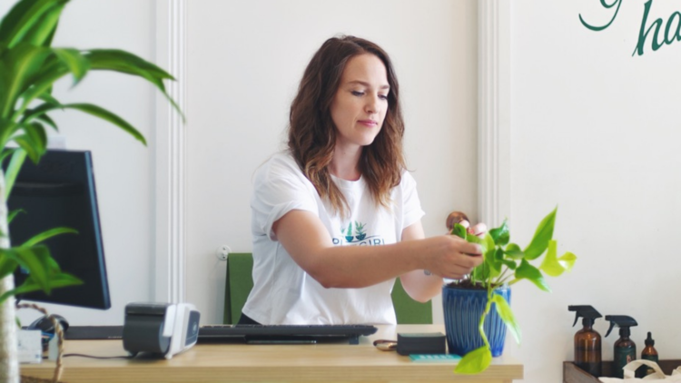 PlantGirl founder and director Felicity Keep sits at desk and tends to plant.