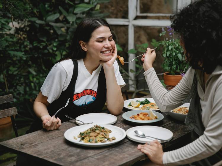 A person feeding another person with fried seafood in garden