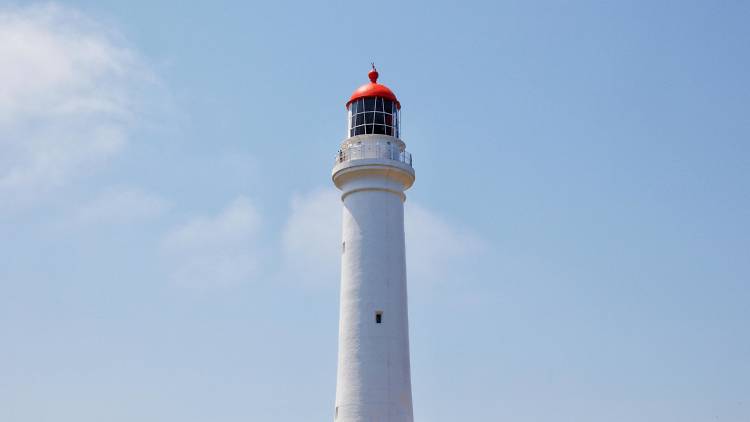 A white lighthouse with a red roof