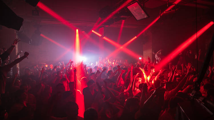 Red lights beam across a crowded dancefloor at fabric