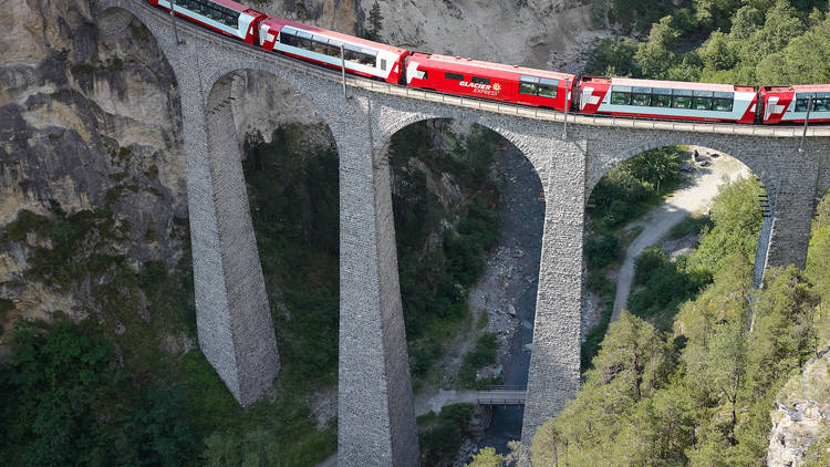 The Glacier Express train crosses a bridge.