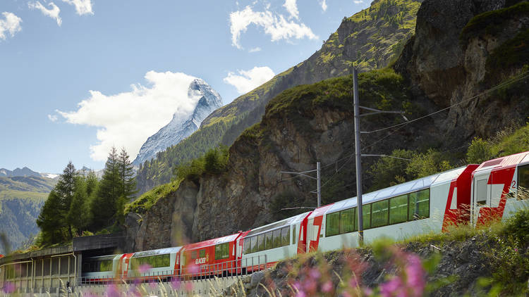 The Glacier Express train travels past mountains.