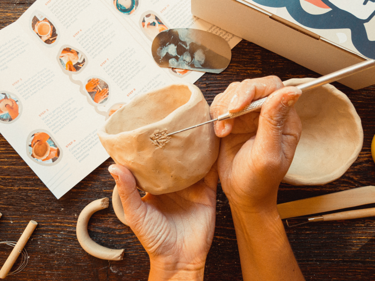 A person etching a clay mug made with a DIY pottery kit by Art by Bossa.