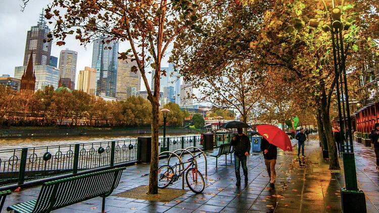 People walking under umbrella along southbank promenade in Melbourne
