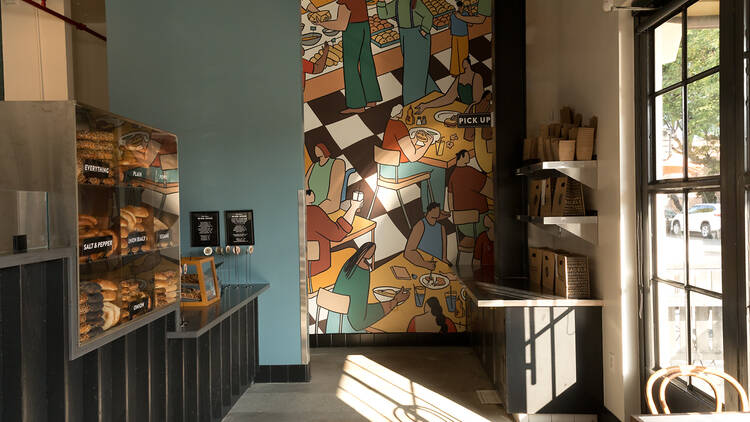 The interior of Wise Sons Jewish Deli in Culver City with bagel counter and mural.