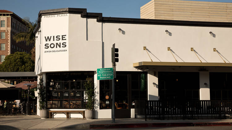 The exterior of Wise Sons Jewish Deli in Culver City located at a street corner with the Culver Hotel in the background.