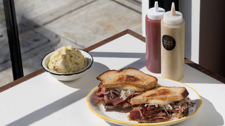 A pastrami sandwich with potato salad on the side sitting on a table at Wise Sons Jewish Deli in Culver City.