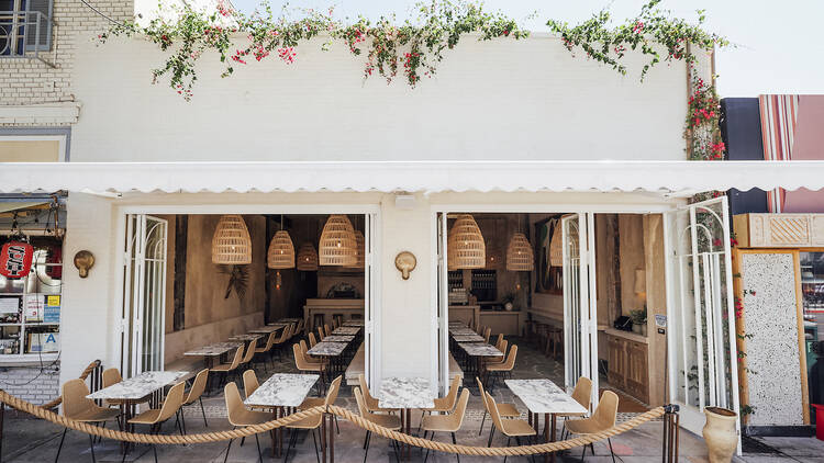 The all-white exterior of Great White Larchmont with indoor and outdoor dining and brown rope fencing.