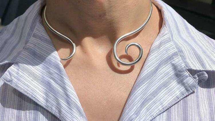 A person wearing a hand-forged sterling silver serpentine necklace.