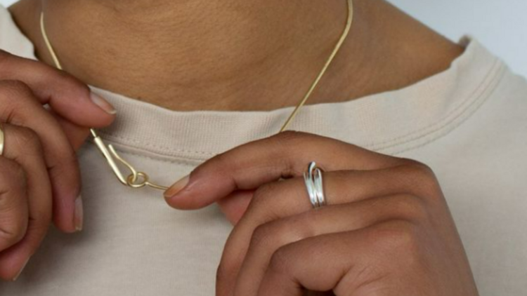 A woman wearing a gold necklace and a silver ring by Lott Studio.
