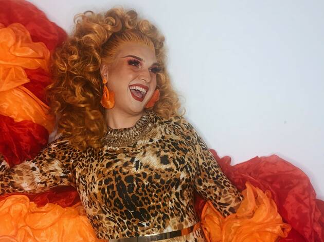 Self Bingolation - Aurora Arsenic Drag queen Aurora Arsenic smiles and strikes a pose while wearing a leopard print onesie