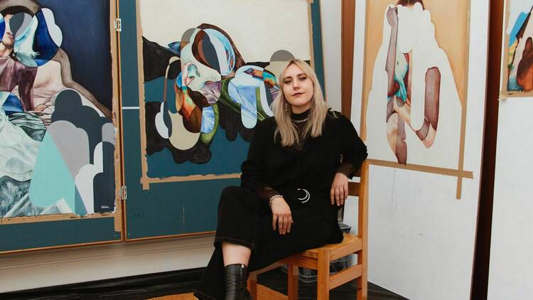 Artist Isabelle de Kleine poses with beautiful abstract paintings of colourful collage-like human figures from debut solo exhibition Un-Define.