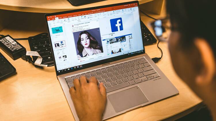 A person browses Facebook on a laptop 