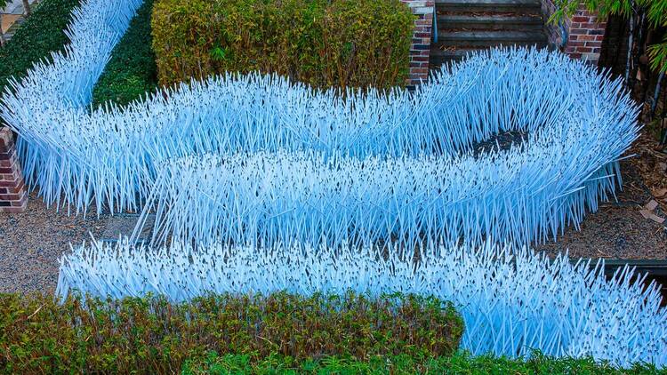 An artwork made up of hundred of old fluorescent tubes arranged like a snake in a garden