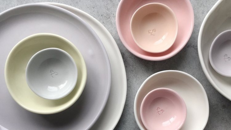 A selection  of handmade ceramic bowls and plates in muted shades of purple, pink and green.