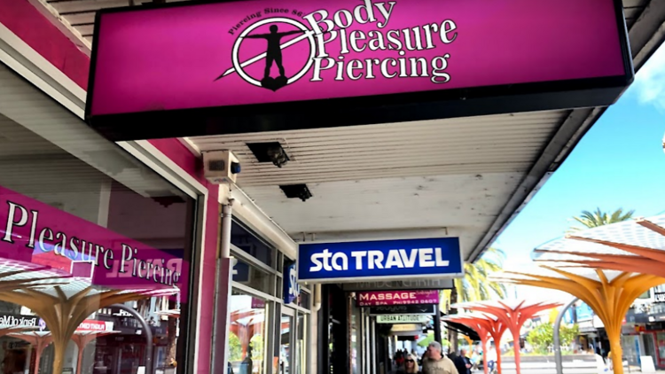 A pink sign outside that reads 'Body Pleasure Piercing.'