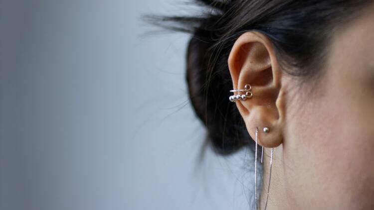 A zoomed-in shot of a woman's ear adorned with several piercings.