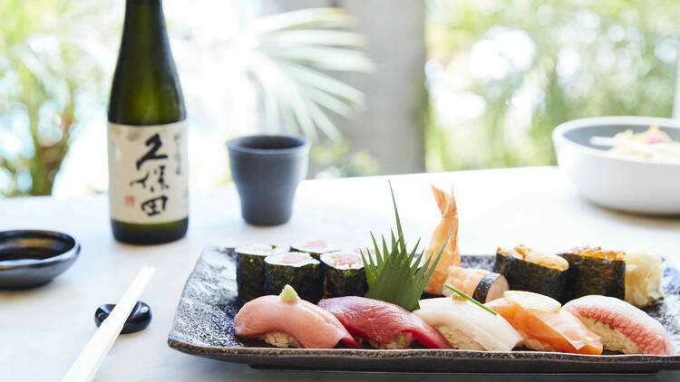 A plate of nigiri and maki at Soko in Santa Monica with sake and a cup in the background.