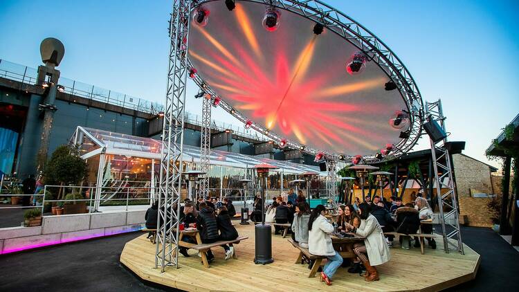 People sitting outside beneath a large lit disc