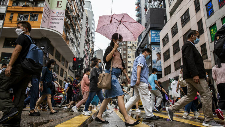 Pedestrians walk on a street in the Wanchai district of Hong Kong on August 6, 2021 