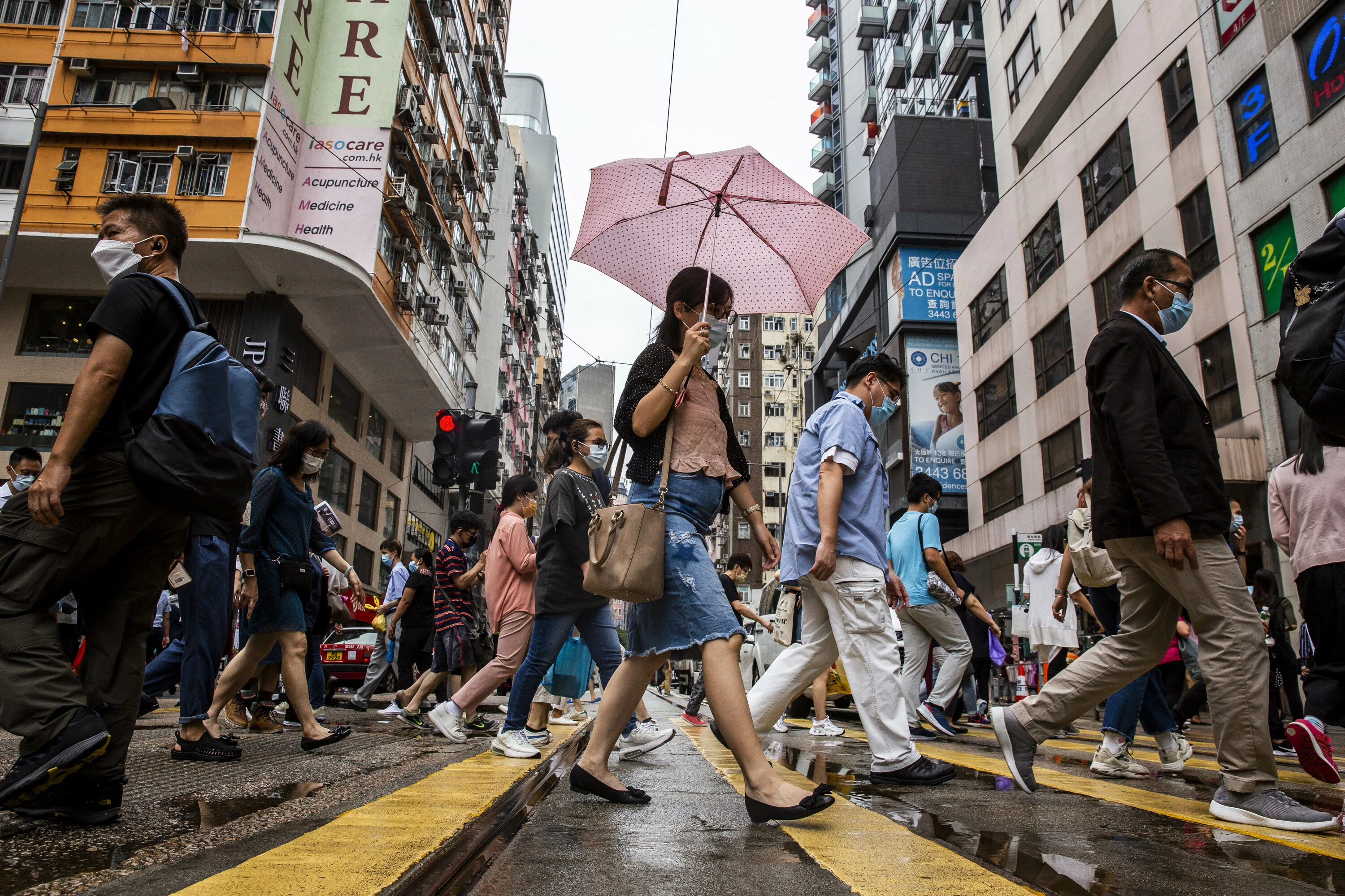 Pedestrians walk on a street in the Wanchai district of Hong Kong on August 6, 2021 