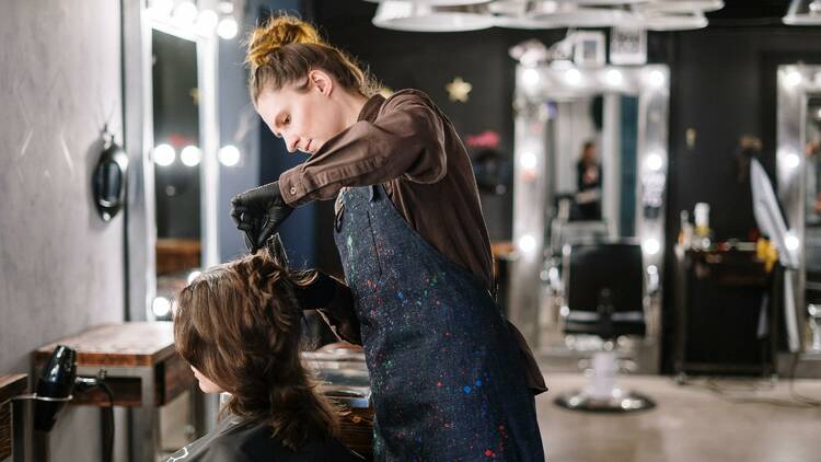 A female hairdresser giving someone a haircut.