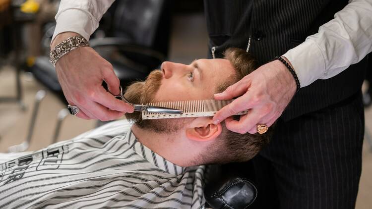 A man receiving a shave and cut at a barbershop.