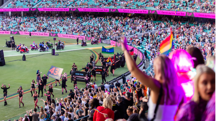 A crowd in the SCG stadium cheers on the Mardi Gras parade.