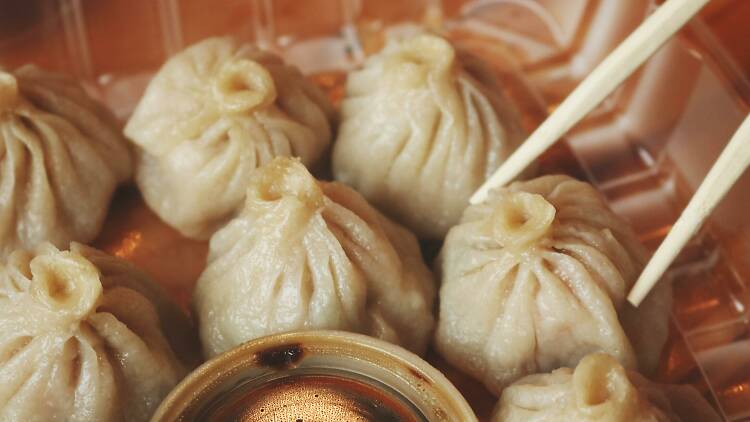 Round pleated dumplings being picked up by chopsticks