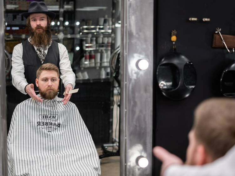 A barber standing behind a man who is about to receive a haircut.