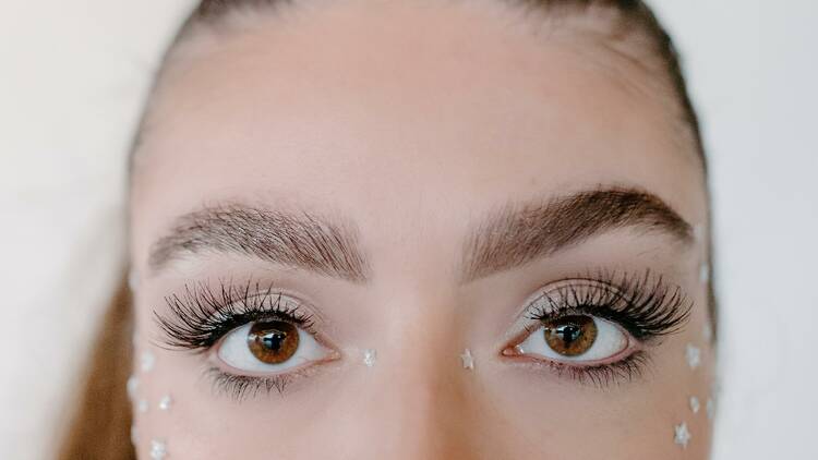 A close up shot of the upper part of a woman's face, particularly her eyebrows and eyes.