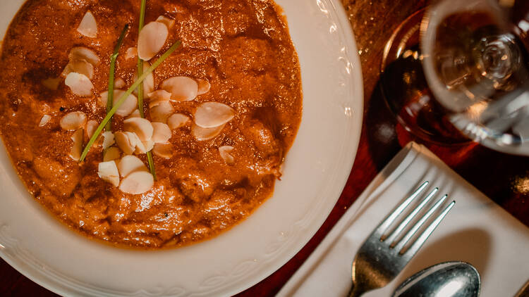 A bird's-eye view of a bowl of butter chicken with flaked almonds on top
