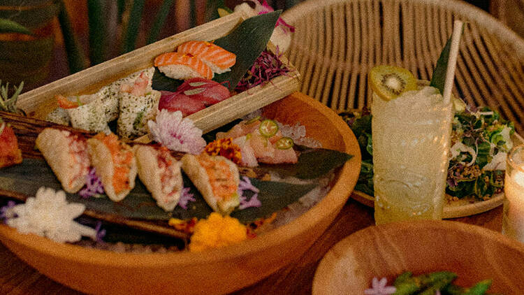 A kiwi-topped tiki drink and sushi platter at Belles Beach House