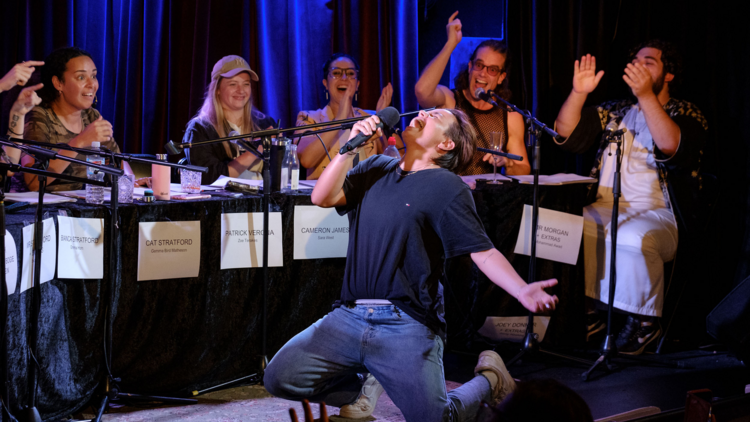 The panel at a Queer Table Reads event cheers as actor Zoe Terakes falls to their knees and proclaims into a microphone
