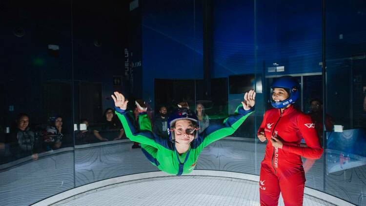 Two individuals in an indoor skydiving chamber at iFly.